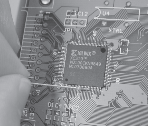 Figure B-3: Applying paste flux to chip pins using a scrap wire repeatedly dipped in flux container